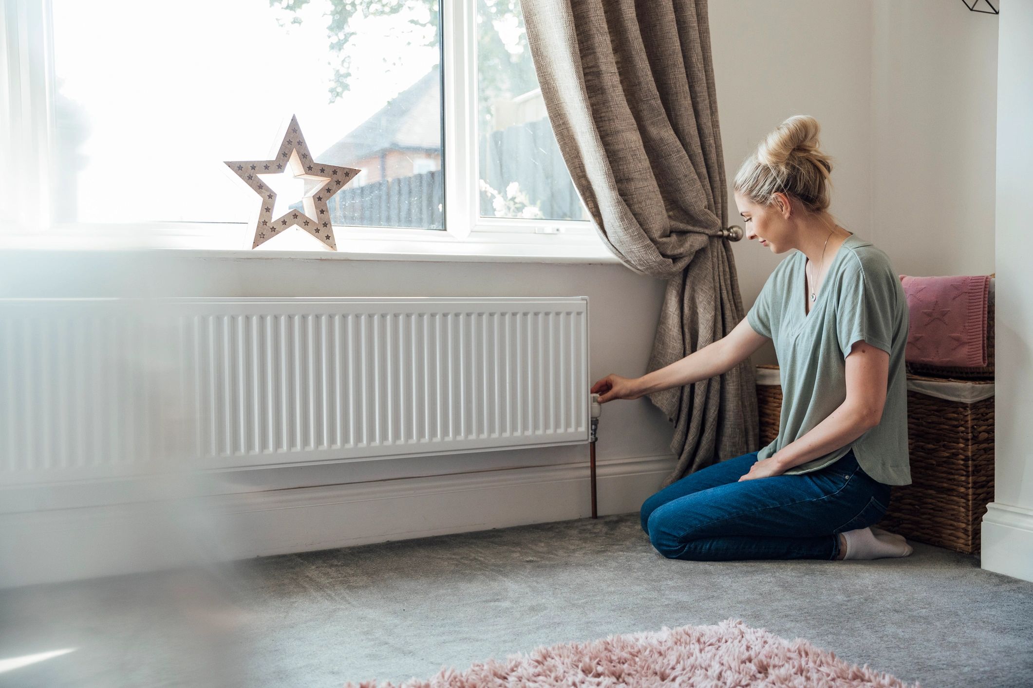 Woman adjusting radiator at home