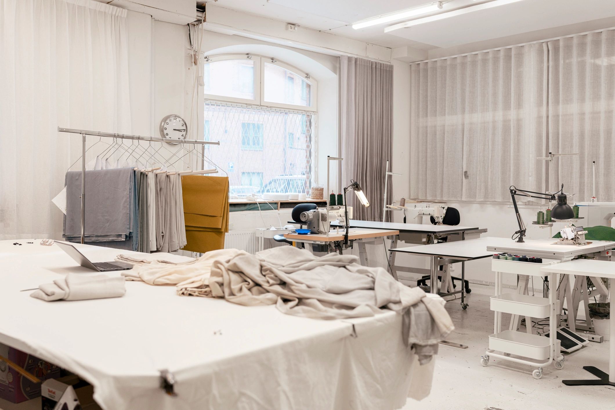 Bright fashion studio workspace with fabric tables and sewing machines