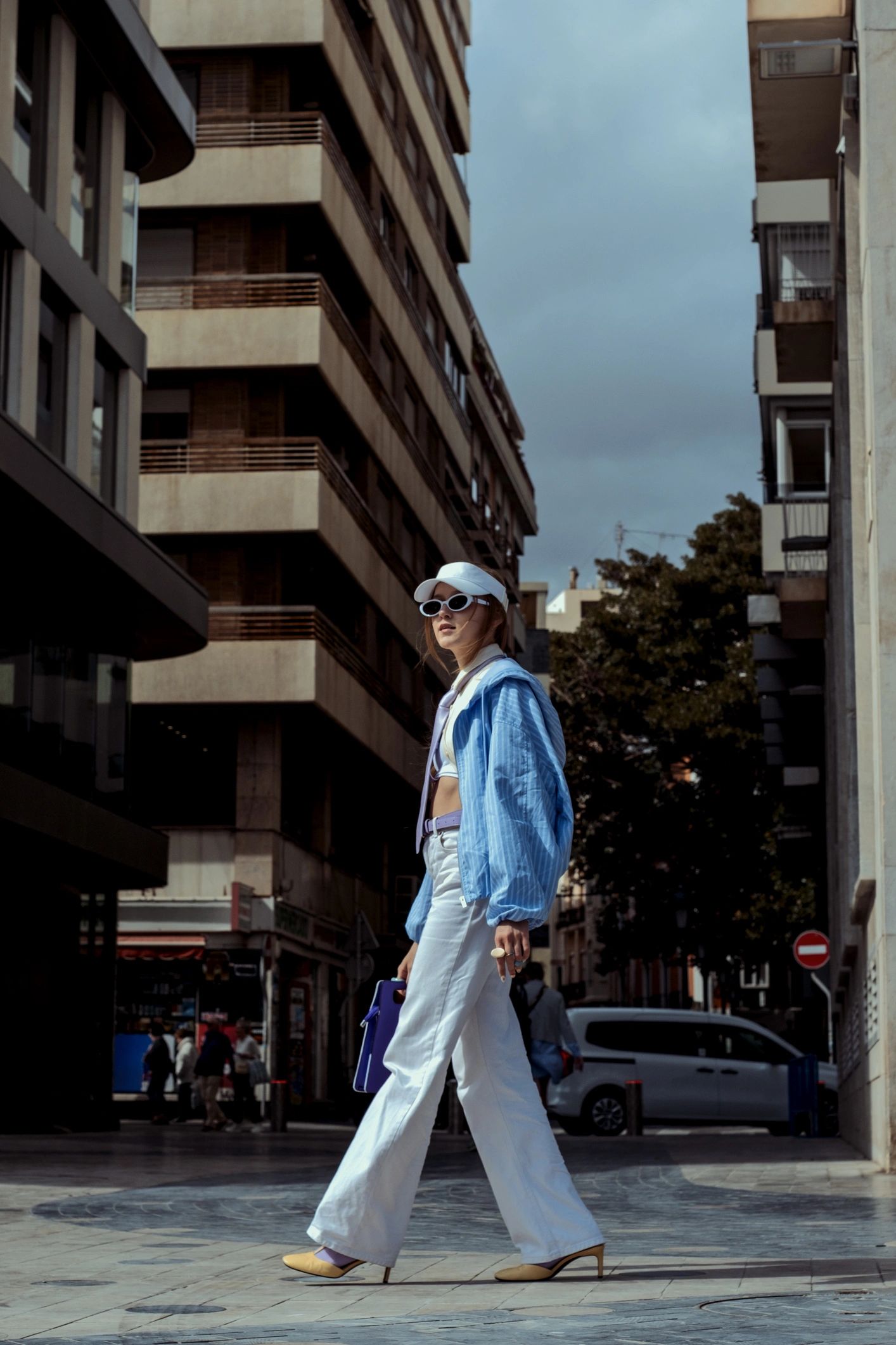 Trendy young adult woman walking city street showcasing street style fashion with urban background