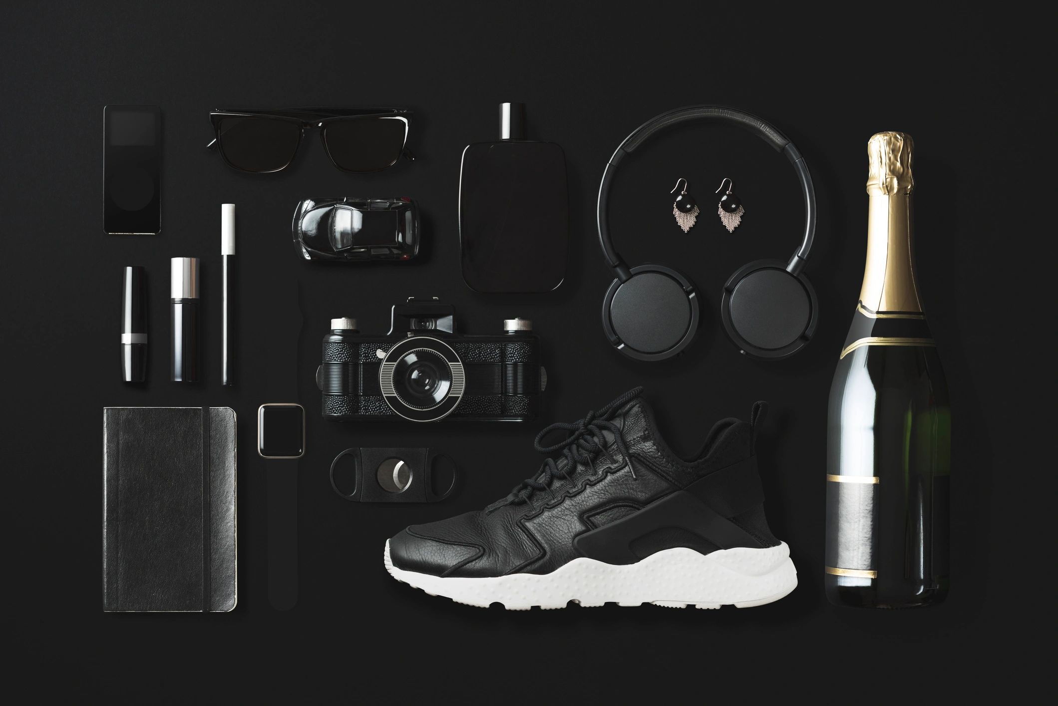 Black fashion and technology items flat lay on black background